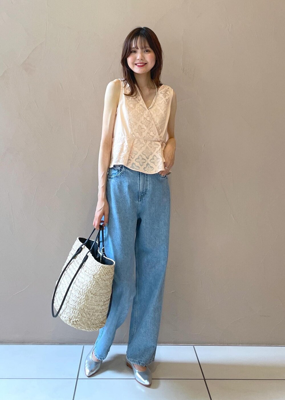 ホワイト系のかごバッグ、ブルー系のデニムパンツ、シルバー系のパンプスを着用したレディースの夏コーディネートの4枚目の写真