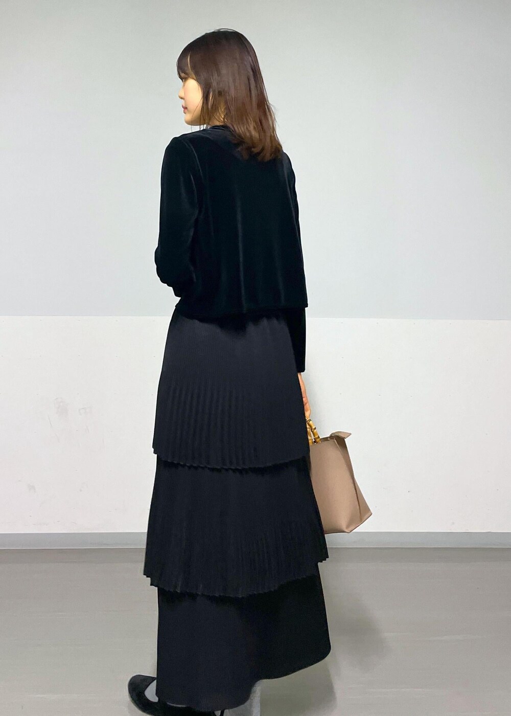 ブラック系のカーディガン/ボレロ、ブラック系のスカート、ベージュ系のハンドバッグを着用したレディースの冬コーディネートの7枚目の写真