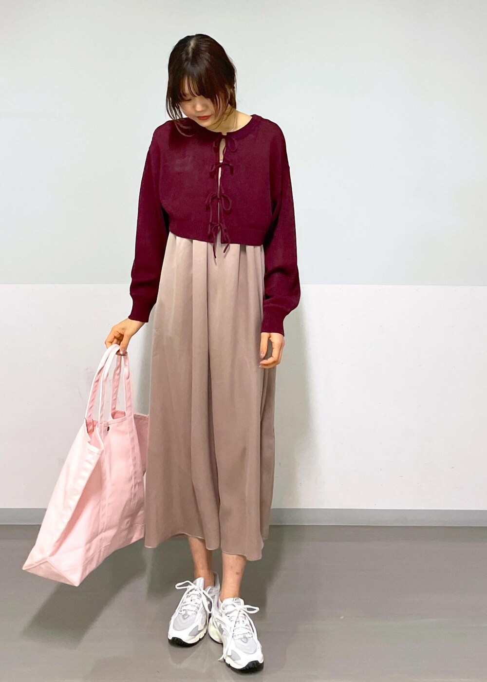 レッド系のニット/セーター、イエロー系のワンピース、ホワイト系のスニーカーを着用したレディースの春コーディネートの5枚目の写真