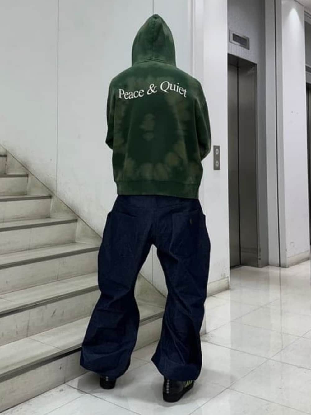 グリーン系のスウェット、グレー系のキャップを着用したメンズの冬コーディネートの2枚目の写真