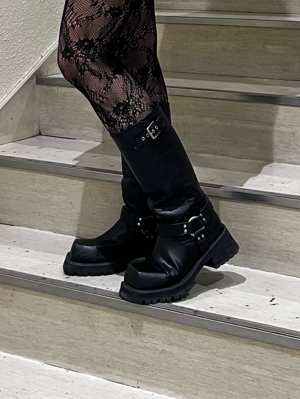 シルバー系のハンドバッグ、ブラック系のスカート、ブラック系のブーツを着用したレディースの冬コーディネートの5枚目の写真