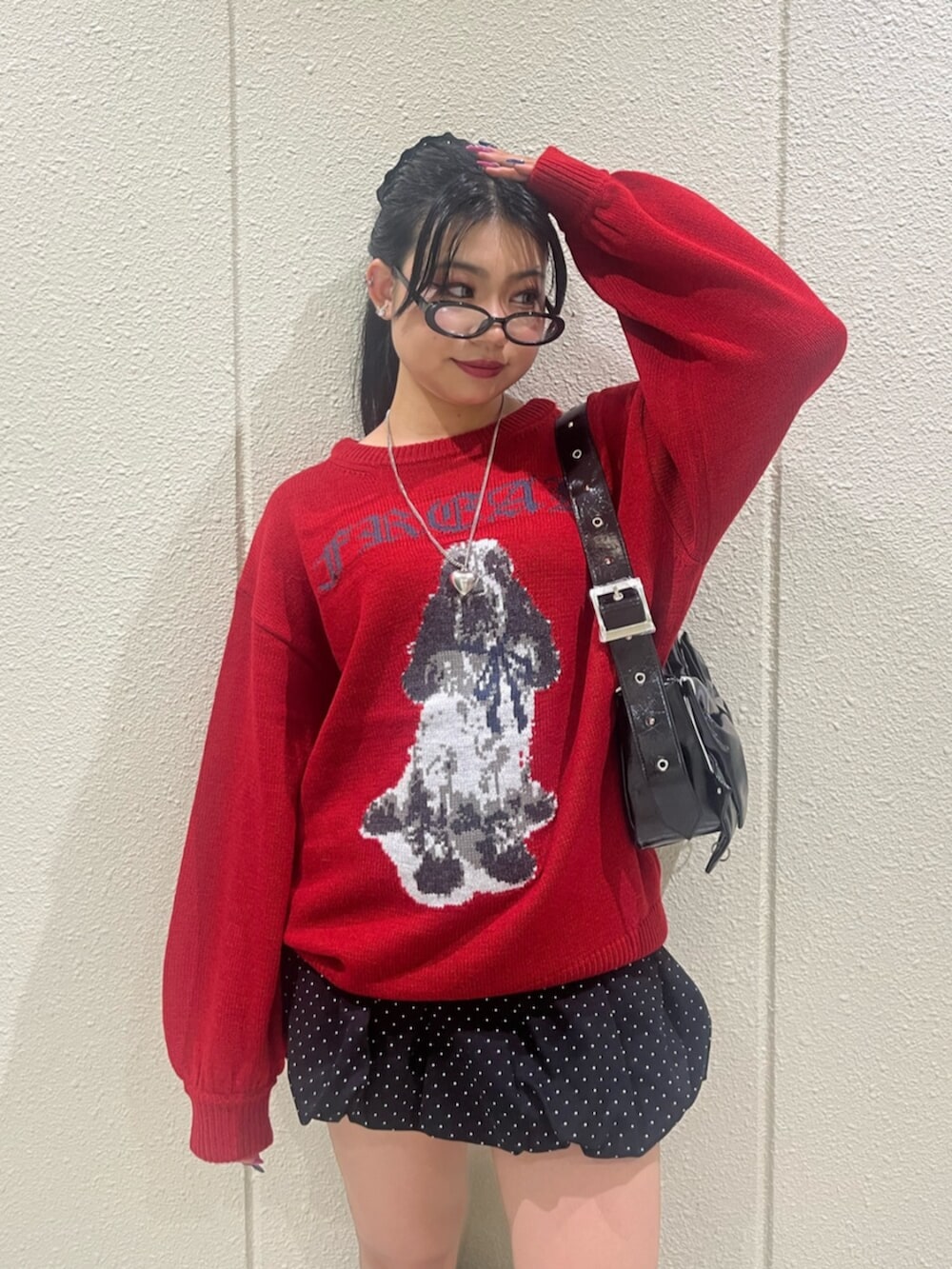 レッド系のニット/セーター、ブラック系のスカート、ブラック系のブーツを着用したレディースの秋コーディネートの5枚目の写真