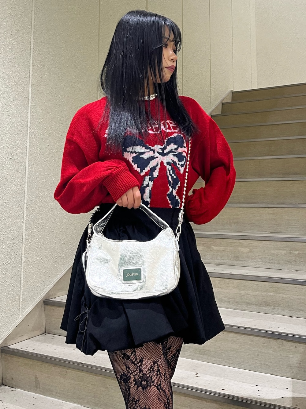 シルバー系のハンドバッグ、ブラック系のスカート、ブラック系のブーツを着用したレディースの冬コーディネートの4枚目の写真