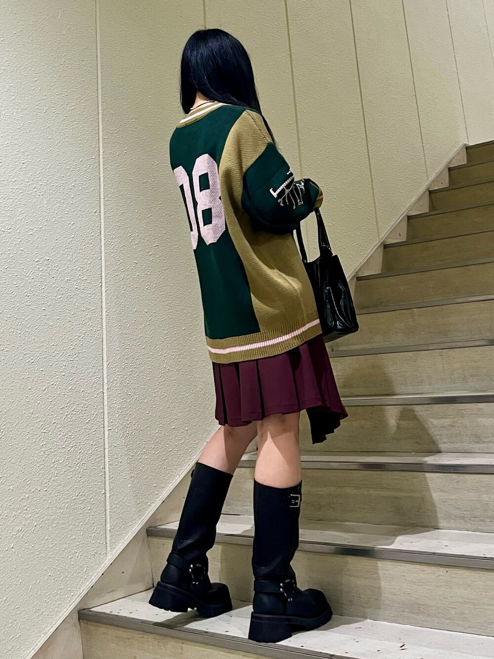 ブラック系のニット/セーター、レッド系のスカート、ブラック系のハンドバッグを着用したレディースの秋コーディネートの4枚目の写真