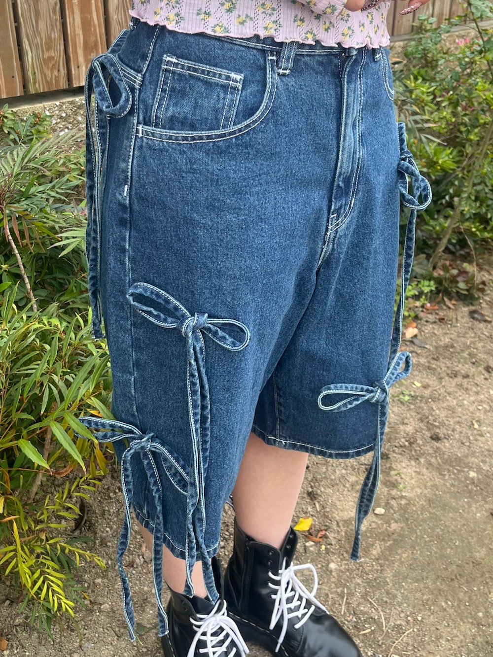 ブルー系のデニムパンツ、ピンク系のアンサンブル、ゴールド系のチョーカーを着用したレディースの春コーディネートの6枚目の写真