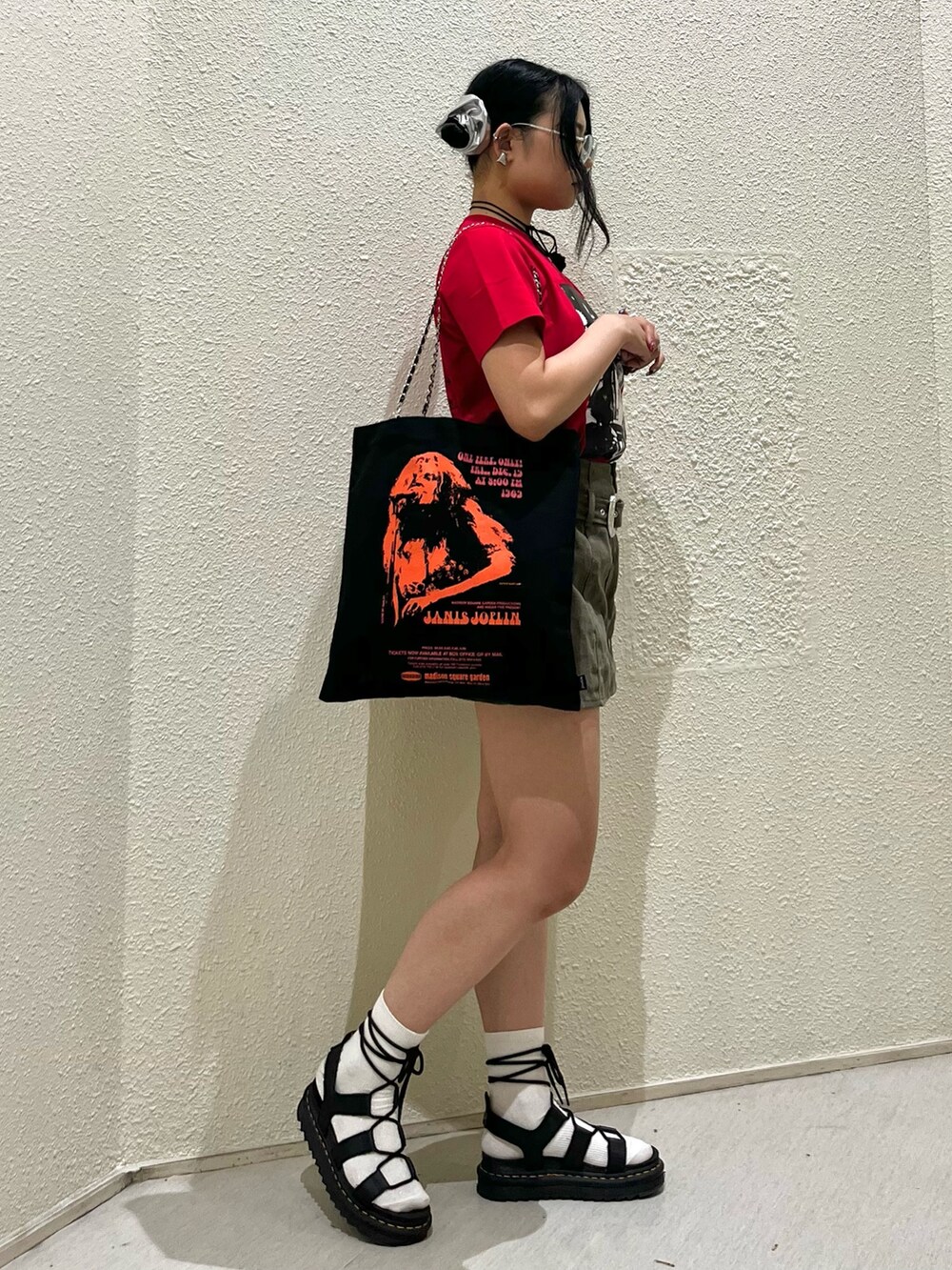 レッド系のTシャツ/カットソー、グリーン系のスカート、ブラック系のトートバッグを着用したレディースの夏コーディネートの2枚目の写真