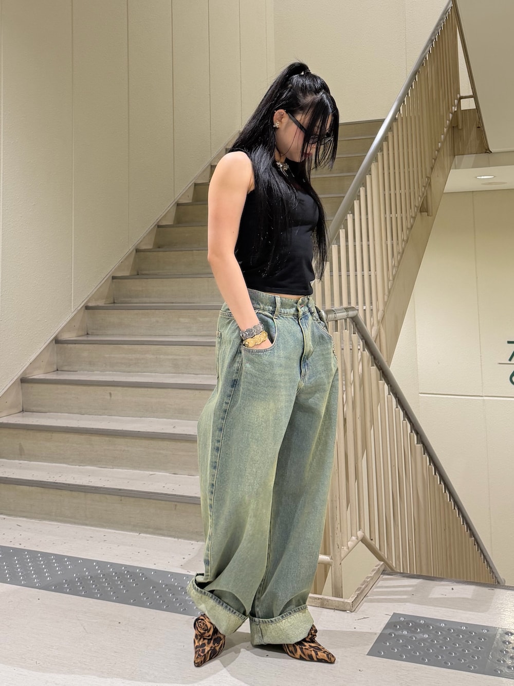 ブルー系のデニムパンツ、ブラック系のタンクトップ、ブラウン系のパンプスを着用したレディースの春コーディネートの2枚目の写真