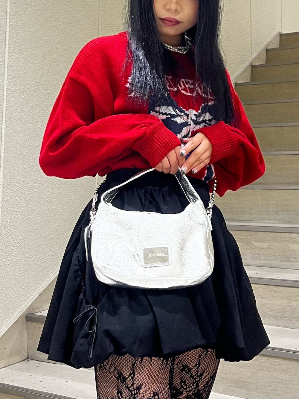 シルバー系のハンドバッグ、ブラック系のスカート、ブラック系のブーツを着用したレディースの冬コーディネートの6枚目の写真