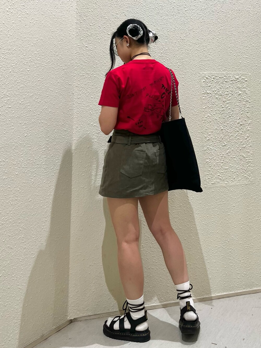 レッド系のTシャツ/カットソー、グリーン系のスカート、ブラック系のトートバッグを着用したレディースの夏コーディネートの3枚目の写真