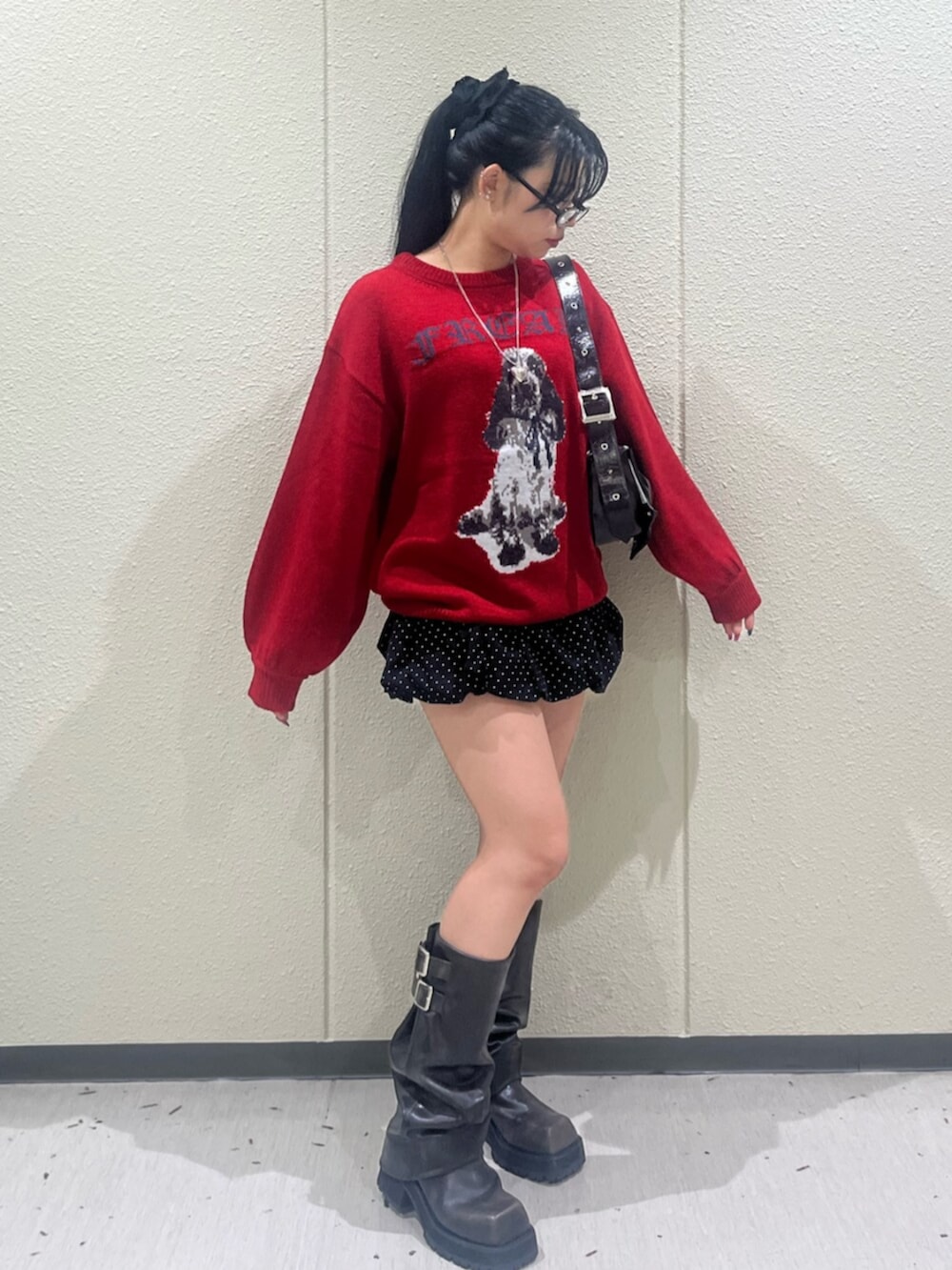 レッド系のニット/セーター、ブラック系のスカート、ブラック系のブーツを着用したレディースの秋コーディネートの2枚目の写真