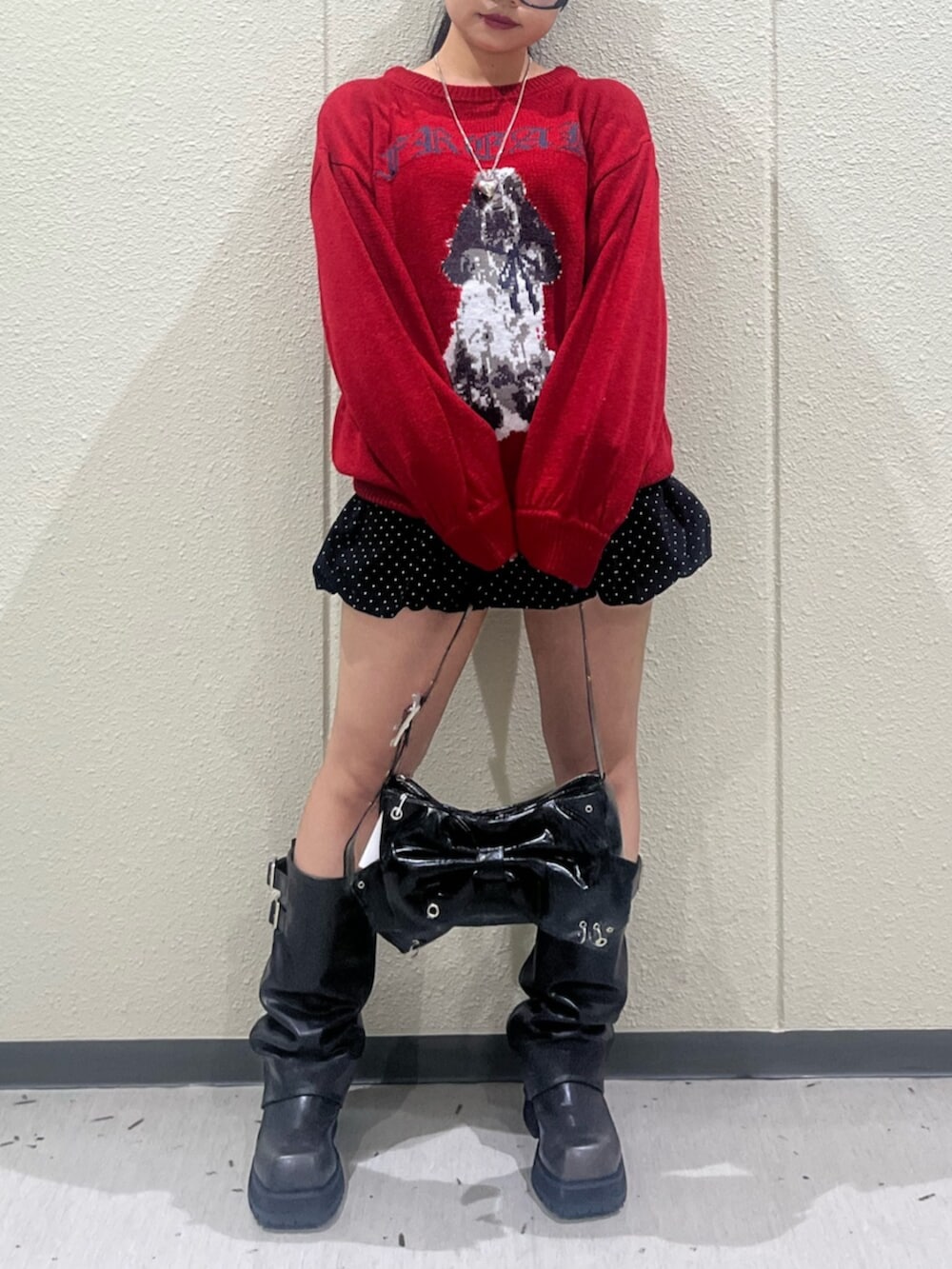 レッド系のニット/セーター、ブラック系のスカート、ブラック系のブーツを着用したレディースの秋コーディネートの6枚目の写真