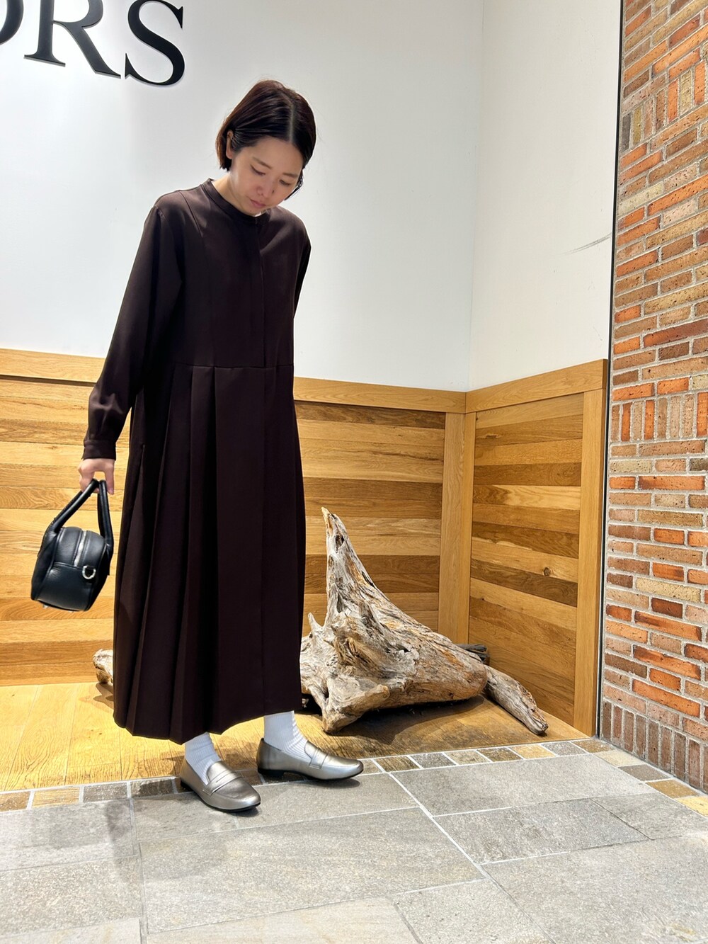 ブラック系のショルダーバッグ、ブラウン系のワンピースを着用したレディースの秋コーディネートの2枚目の写真