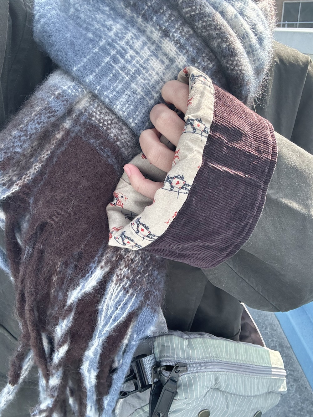 ホワイト系のスニーカー、グリーン系のミリタリージャケット、グレー系のデニムパンツを着用したレディースの冬コーディネートの2枚目の写真