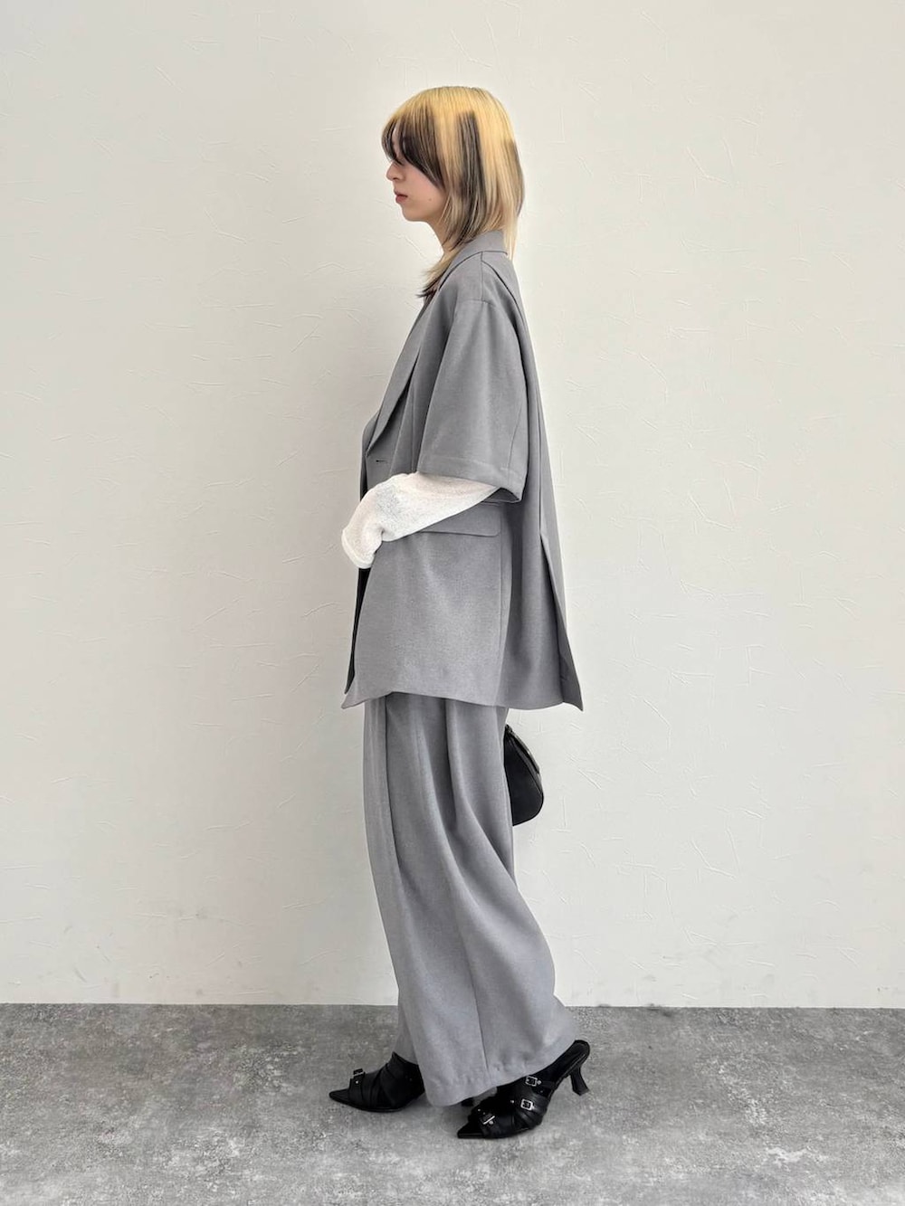 ブラック系のハンドバッグ、グレー系のテーラードジャケット、グレー系のスラックスを着用したレディースの春コーディネートの2枚目の写真