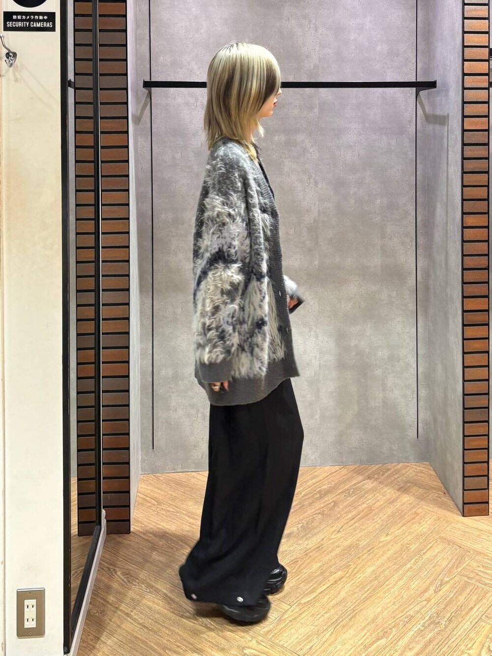 ブラック系のスニーカー、グレー系のカーディガン/ボレロ、ブラック系のスラックスを着用したレディースの秋コーディネートの5枚目の写真