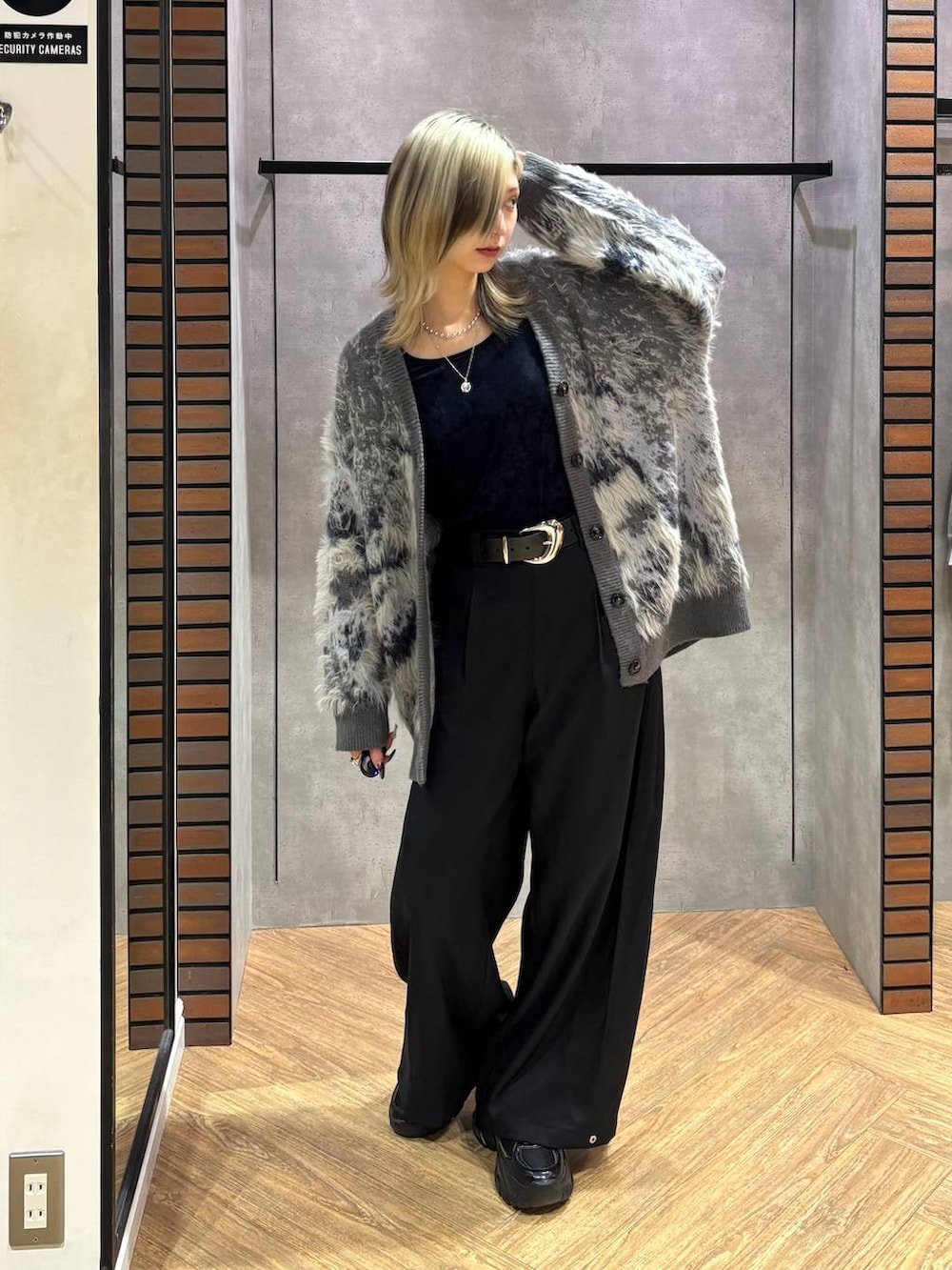 ブラック系のスニーカー、グレー系のカーディガン/ボレロ、ブラック系のスラックスを着用したレディースの秋コーディネートの2枚目の写真