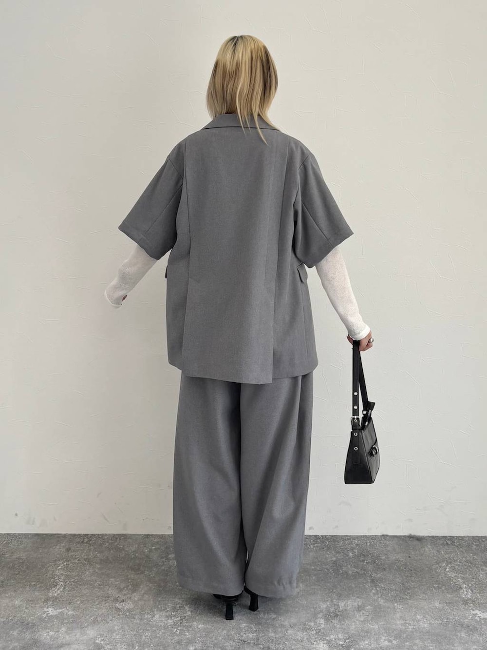 ブラック系のハンドバッグ、グレー系のテーラードジャケット、グレー系のスラックスを着用したレディースの春コーディネートの3枚目の写真