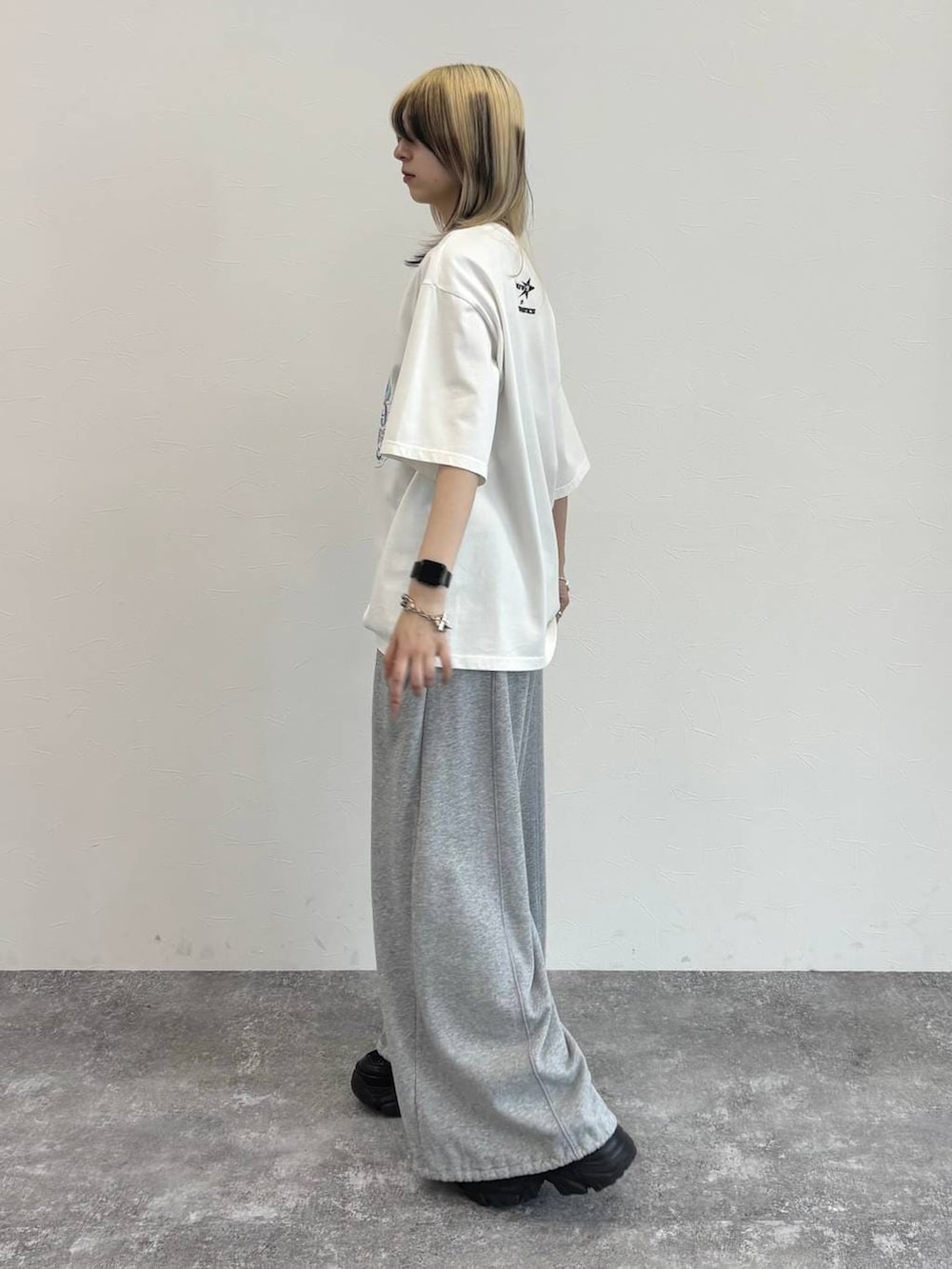 ブラック系のスニーカー、グレー系のスウェットパンツ、ホワイト系のTシャツ/カットソーを着用したレディースの春コーディネートの5枚目の写真