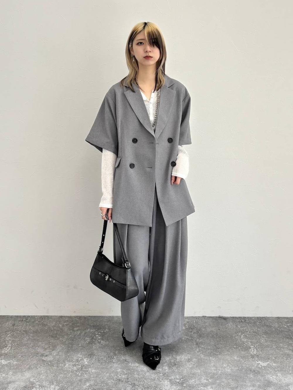 ブラック系のハンドバッグ、グレー系のテーラードジャケット、グレー系のスラックスを着用したレディースの春コーディネートの5枚目の写真