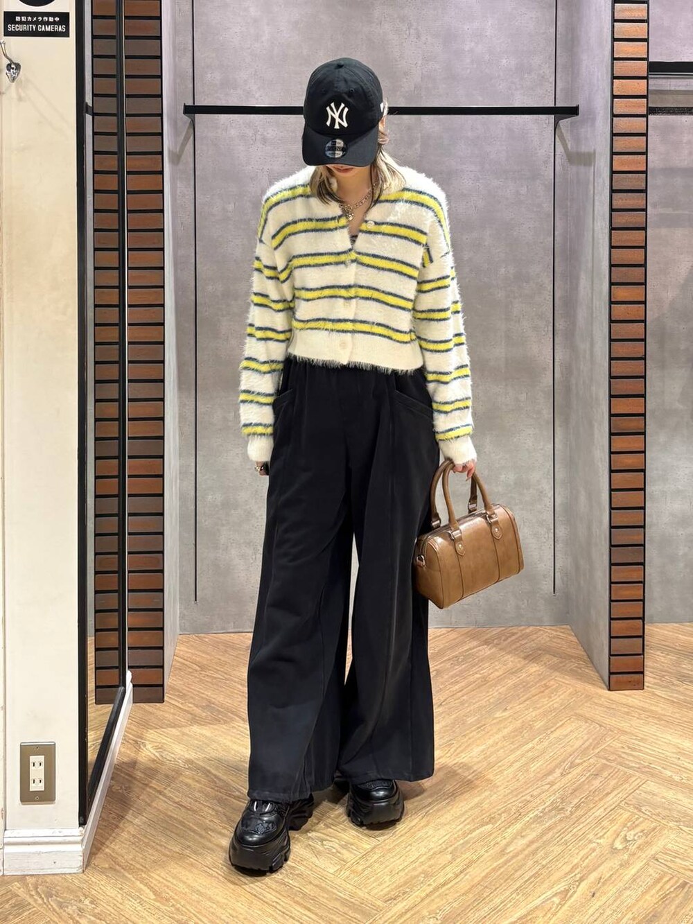 ブラック系のスニーカー、ブラウン系のボストンバッグ、ホワイト系のニット/セーターを着用したレディースの冬コーディネートの3枚目の写真