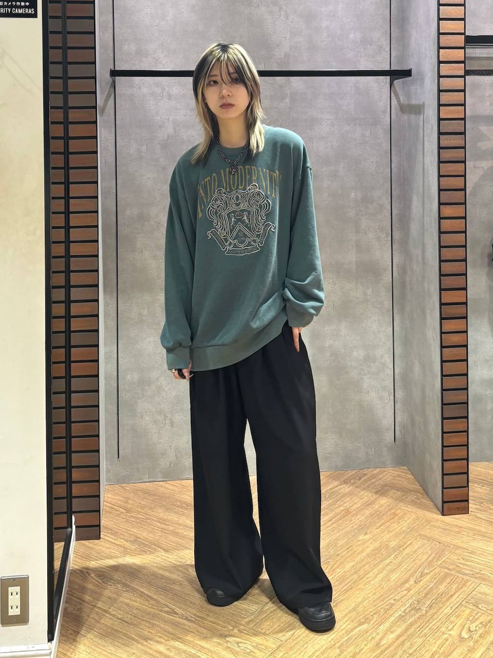 ブラック系のデニムパンツ、グリーン系のスウェット、ブラック系のネックレスを着用したレディースの冬コーディネートの6枚目の写真