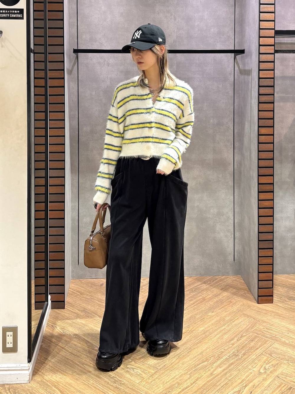 ブラック系のスニーカー、ブラウン系のボストンバッグ、ホワイト系のニット/セーターを着用したレディースの冬コーディネートの2枚目の写真