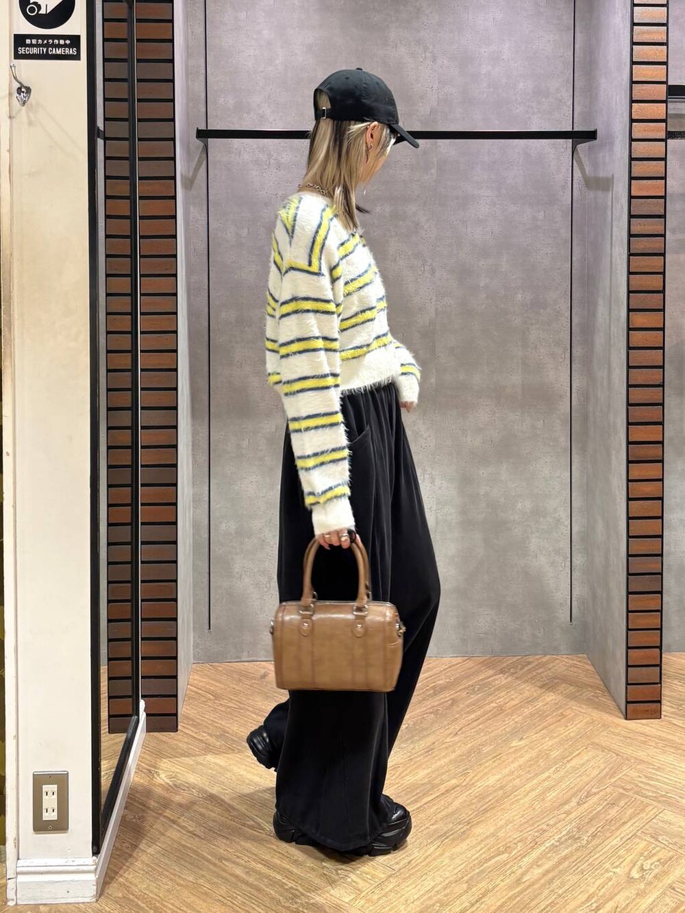 ブラック系のスニーカー、ブラウン系のボストンバッグ、ホワイト系のニット/セーターを着用したレディースの冬コーディネートの6枚目の写真