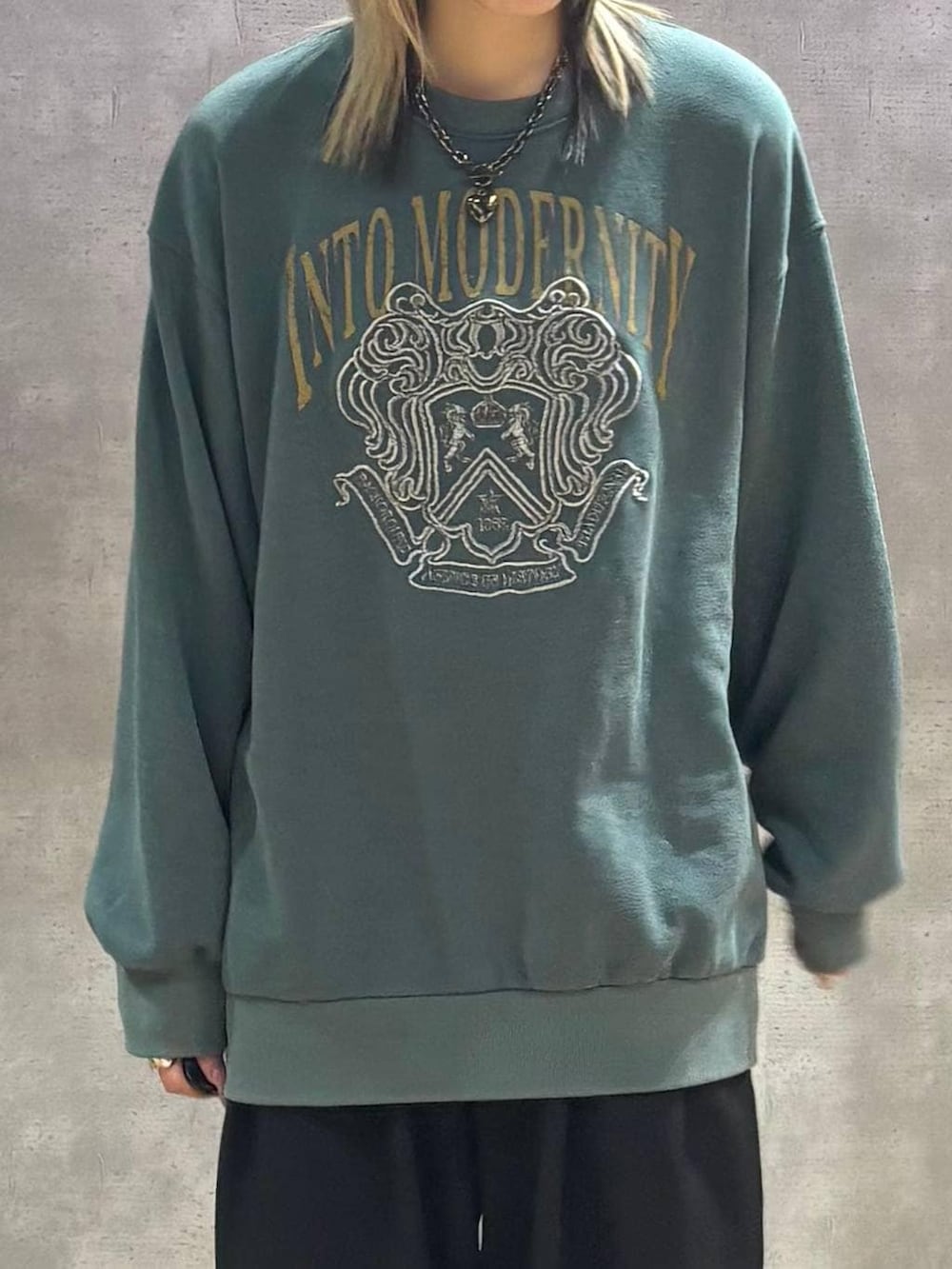 ブラック系のデニムパンツ、グリーン系のスウェット、ブラック系のネックレスを着用したレディースの冬コーディネートの2枚目の写真