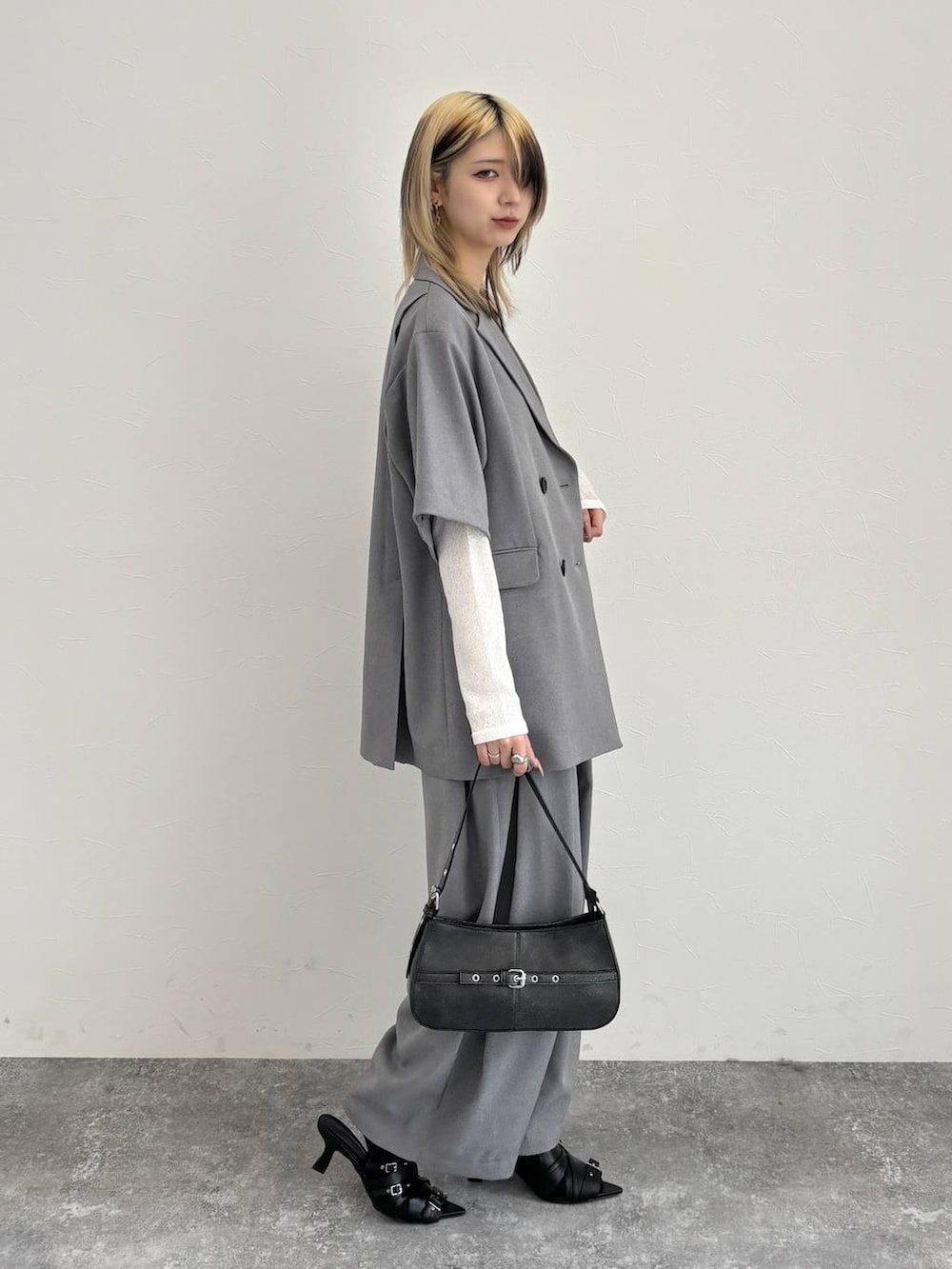 ブラック系のハンドバッグ、グレー系のテーラードジャケット、グレー系のスラックスを着用したレディースの春コーディネートの4枚目の写真