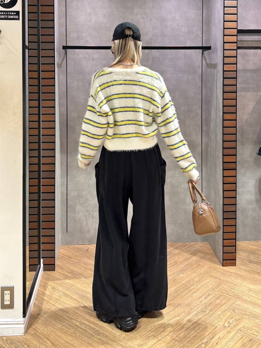 ブラック系のスニーカー、ブラウン系のボストンバッグ、ホワイト系のニット/セーターを着用したレディースの冬コーディネートの5枚目の写真