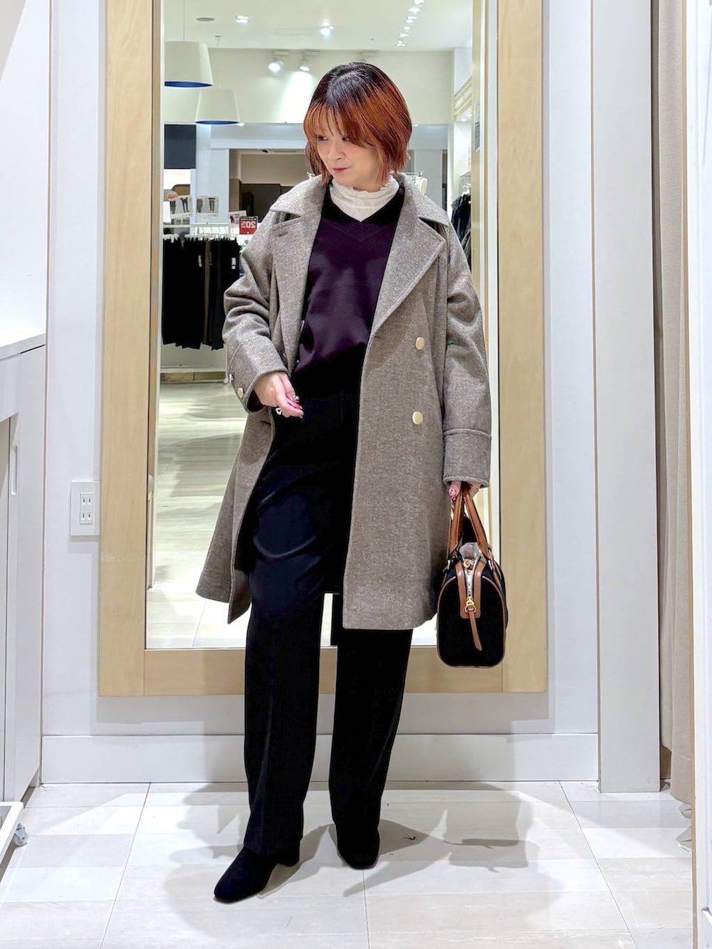 ブラウン系のチェスターコート、ブラウン系のニット/セーター、ブラック系のその他パンツを着用したレディースの冬コーディネートの4枚目の写真