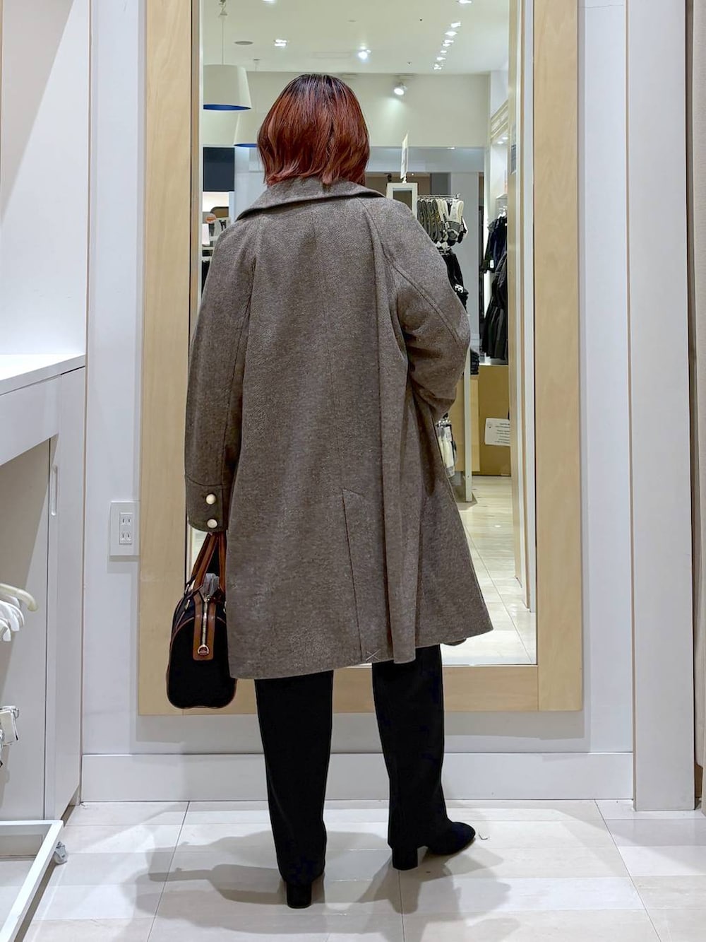 ブラウン系のチェスターコート、ブラウン系のニット/セーター、ブラック系のその他パンツを着用したレディースの冬コーディネートの3枚目の写真