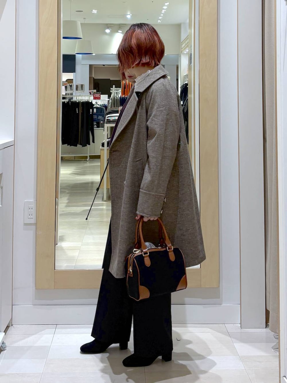 ブラウン系のチェスターコート、ブラウン系のニット/セーター、ブラック系のその他パンツを着用したレディースの冬コーディネートの2枚目の写真