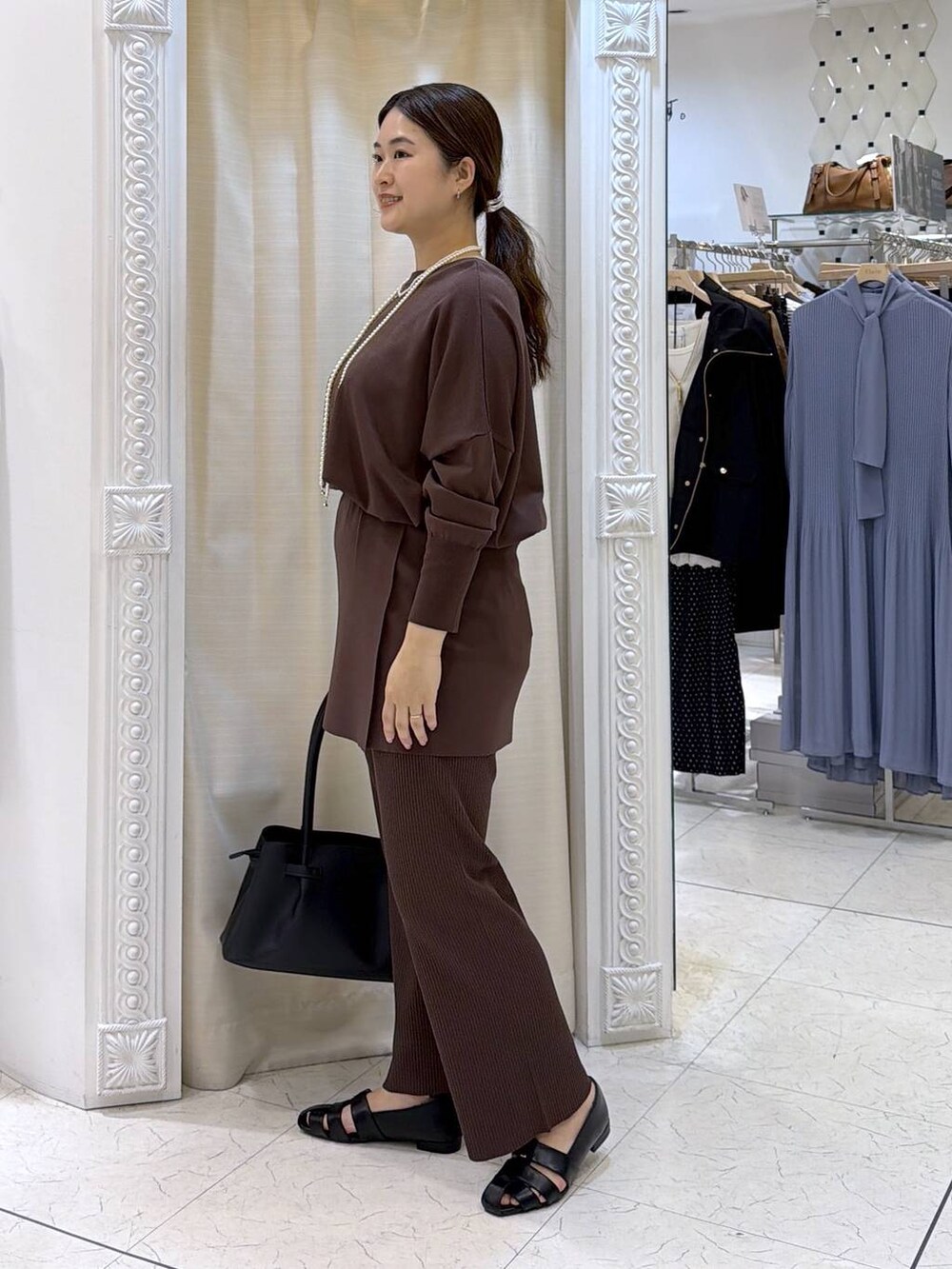 ブラック系のハンドバッグ、ブラック系のパンプス、ブラウン系のその他パンツを着用したレディースの春コーディネートの2枚目の写真