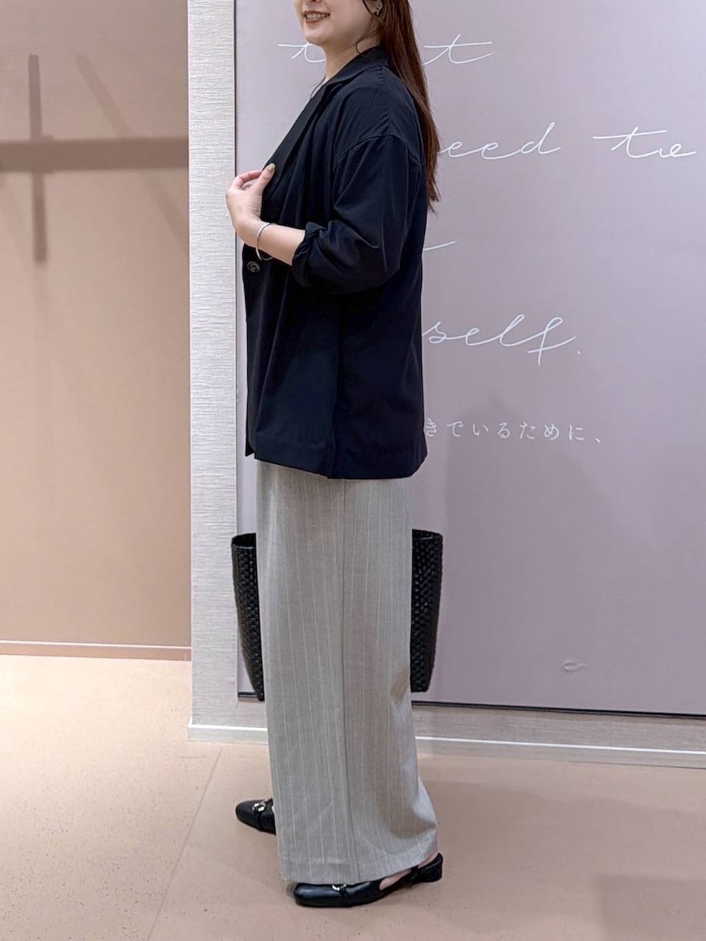 ブラック系のパンプス、ブラック系のテーラードジャケット、ブラック系のかごバッグを着用したレディースの夏コーディネートの2枚目の写真