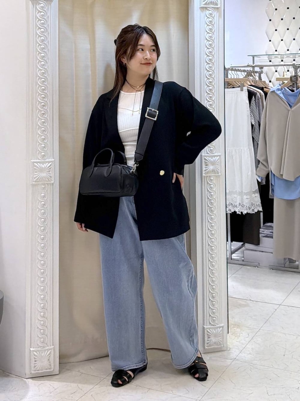 ブルー系のデニムパンツ、ブラック系のパンプス、ブラック系のボストンバッグを着用したレディースの春コーディネートの2枚目の写真