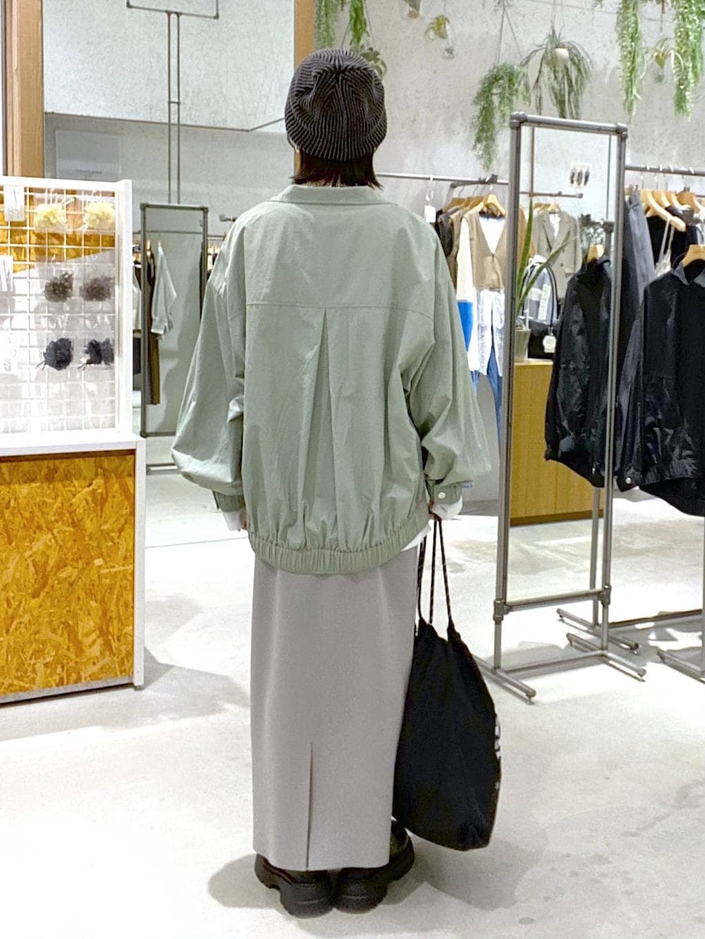 グレー系のスカート、グリーン系のブルゾン、ブラック系のその他シューズを着用したレディースの冬コーディネートの3枚目の写真