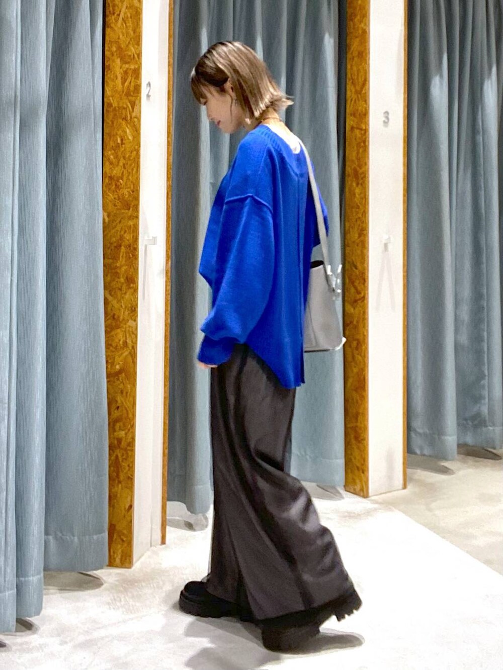 ブルー系のニット/セーター、ブラック系のブーツ、シルバー系のショルダーバッグを着用したレディースの秋コーディネートの2枚目の写真