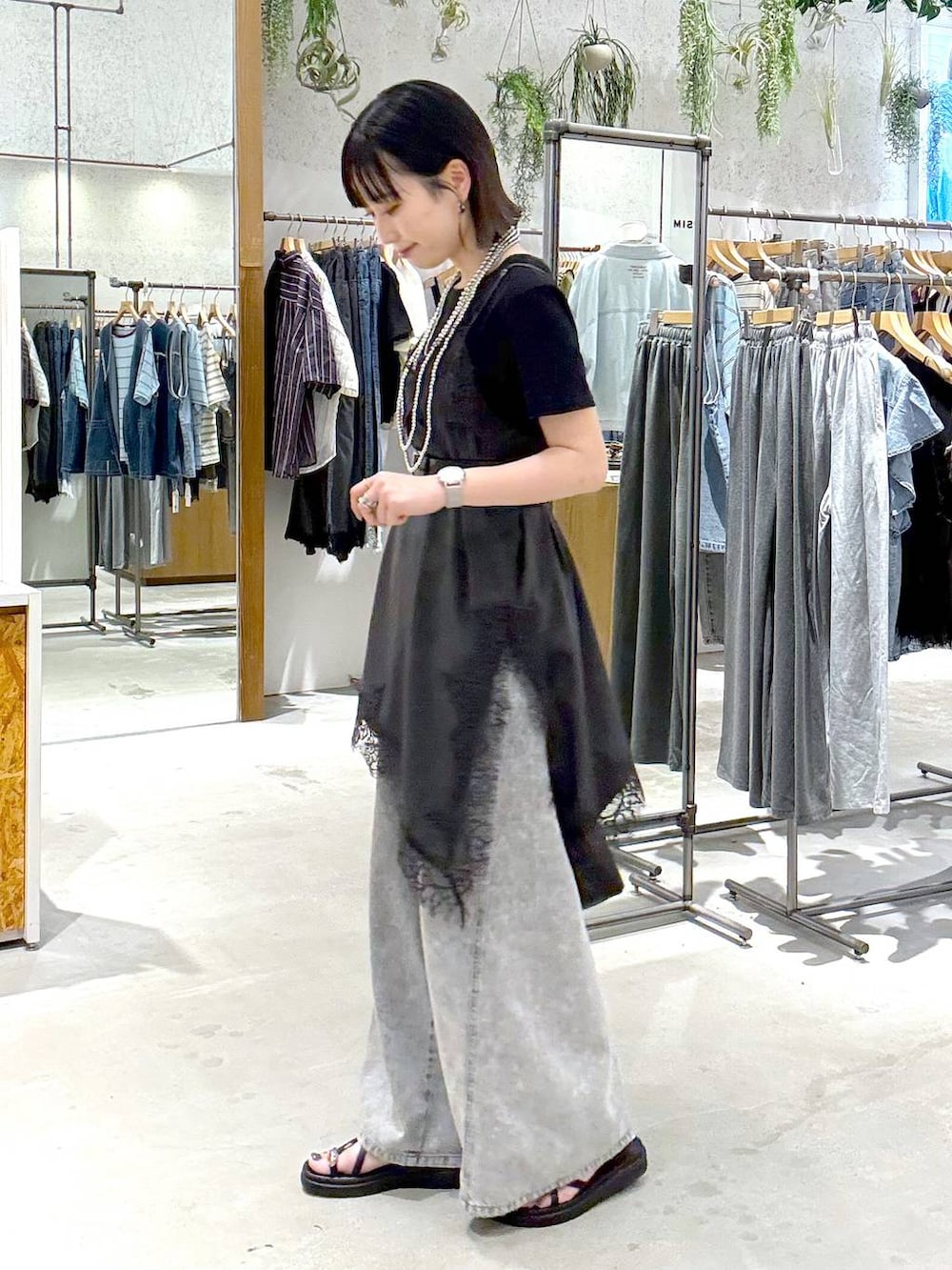 グレー系のデニムパンツ、ブラック系のサンダル、ブラック系のTシャツ/カットソーを着用したレディースの夏コーディネートの2枚目の写真