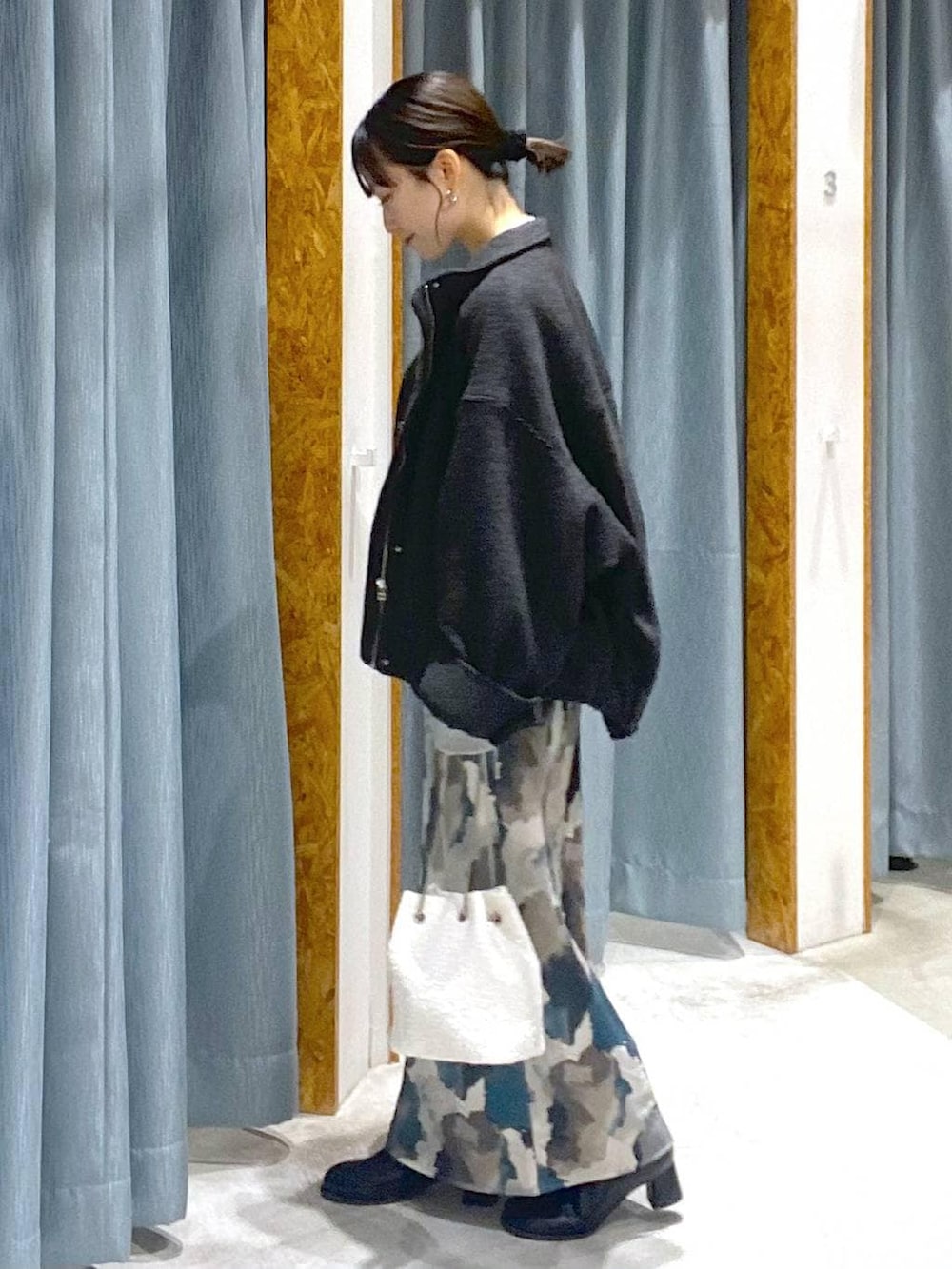 ブラック系のブルゾン、ブラック系のブーツ、ホワイト系のショルダーバッグを着用したレディースの冬コーディネートの2枚目の写真