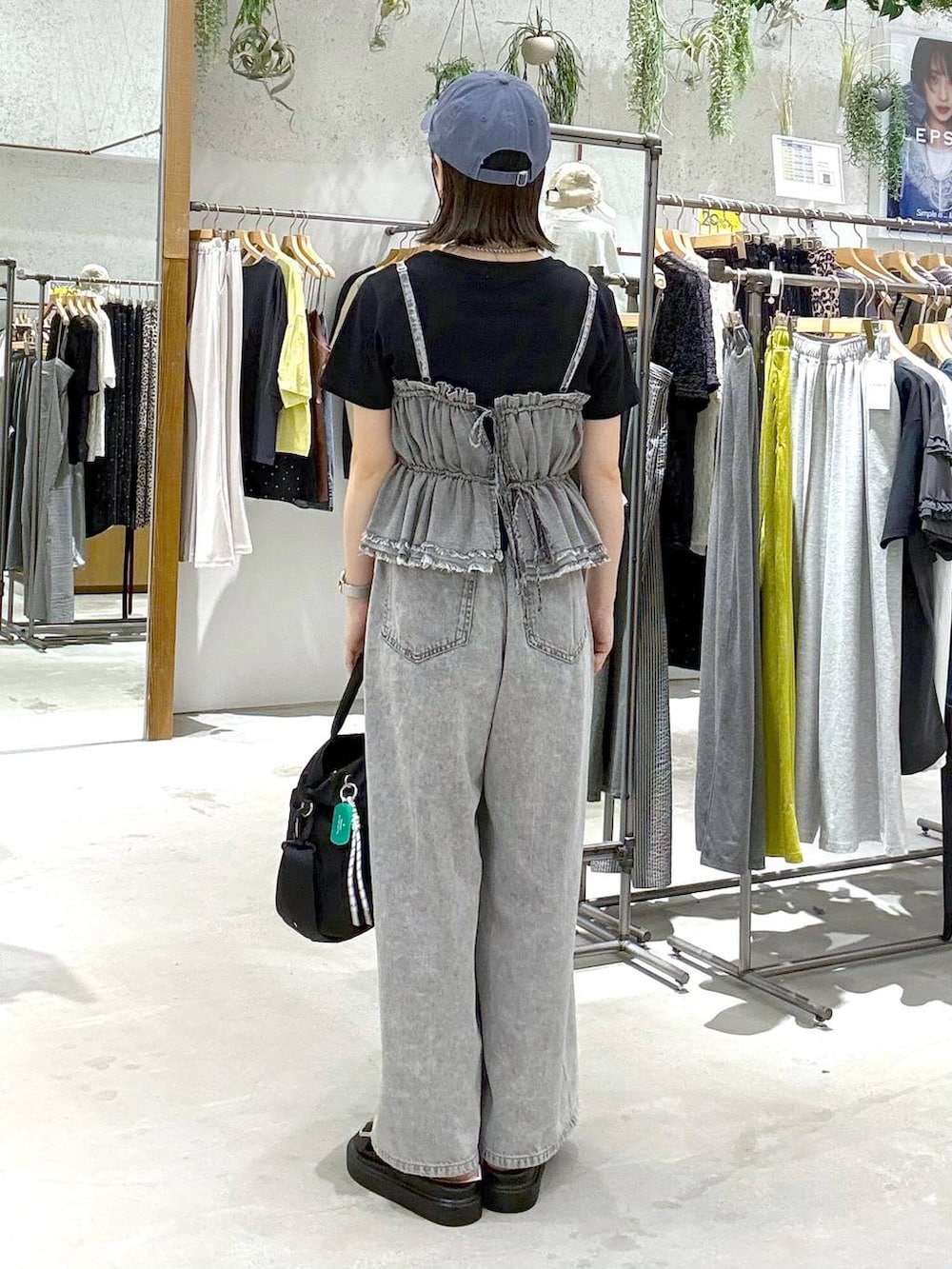 グレー系のデニムパンツ、ブラック系のトートバッグ、ブラック系のサンダルを着用したレディースの春コーディネートの3枚目の写真