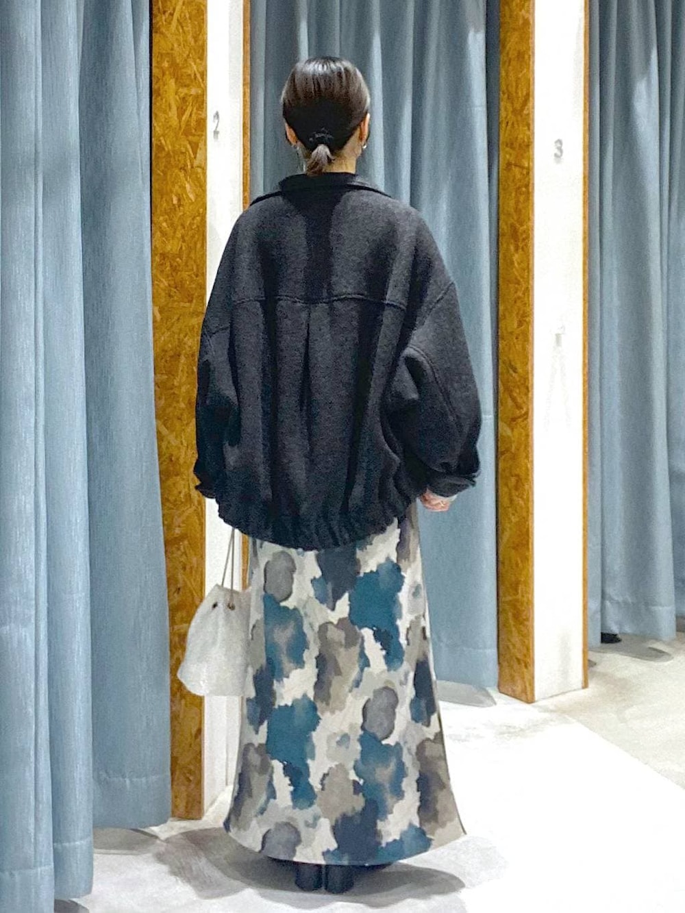 ブラック系のブルゾン、ブラック系のブーツ、ホワイト系のショルダーバッグを着用したレディースの冬コーディネートの3枚目の写真