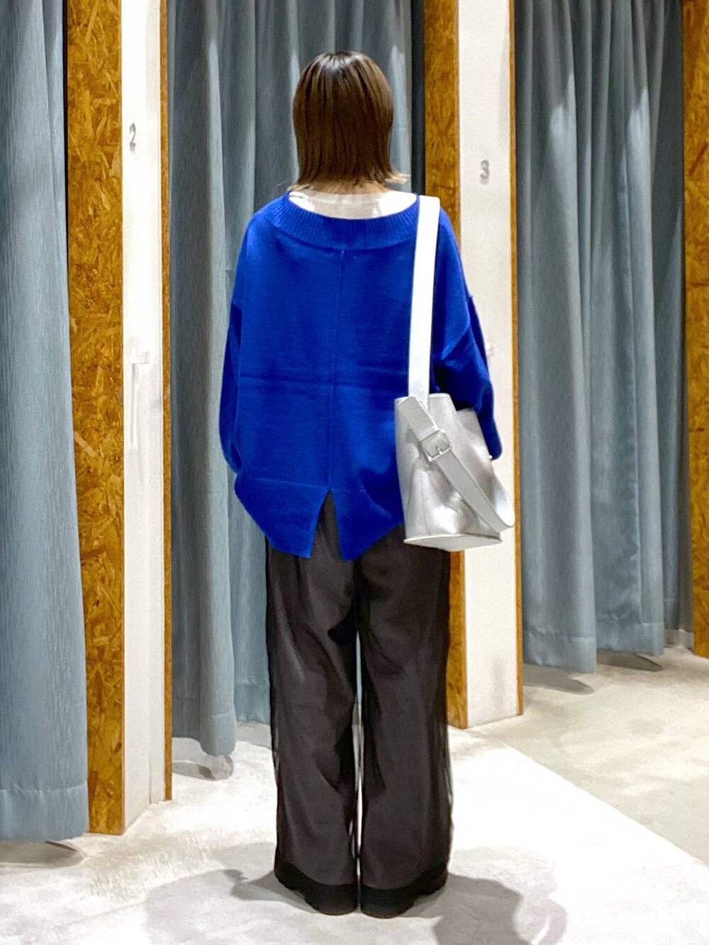 ブルー系のニット/セーター、ブラック系のブーツ、シルバー系のショルダーバッグを着用したレディースの秋コーディネートの3枚目の写真