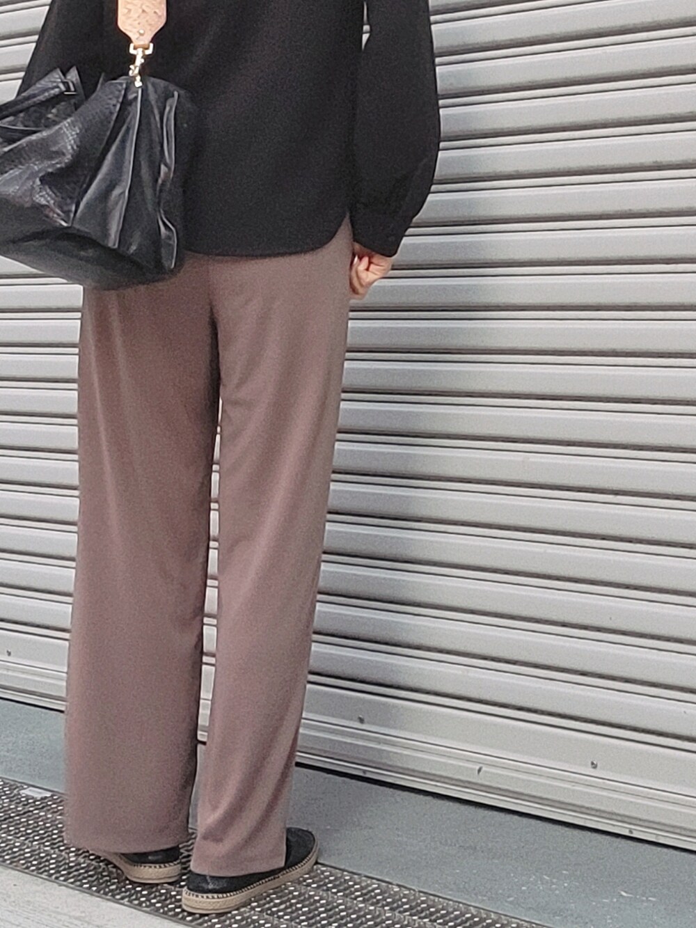 ブラック系のスリッポン、ブラウン系のパンツ、ブラック系のトートバッグを着用したレディースの夏コーディネートの2枚目の写真