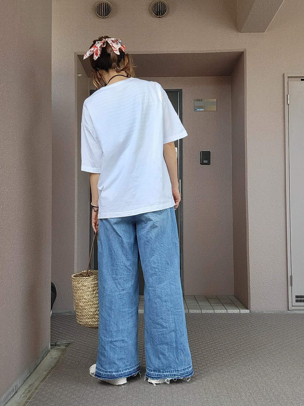 ベージュ系のかごバッグ、ブルー系のデニムパンツ、ホワイト系のサンダルを着用したレディースの春コーディネートの2枚目の写真