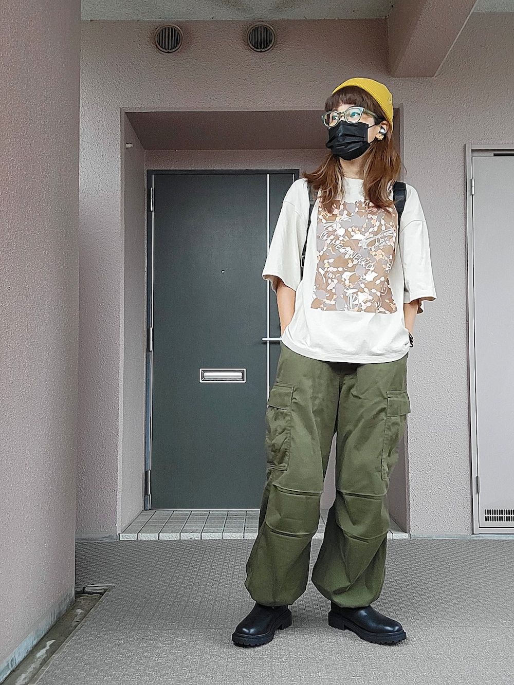 グリーン系のカーゴパンツ、ブラック系のバックパック/リュック、ベージュ系のTシャツ/カットソーを着用したレディースの秋コーディネートの2枚目の写真