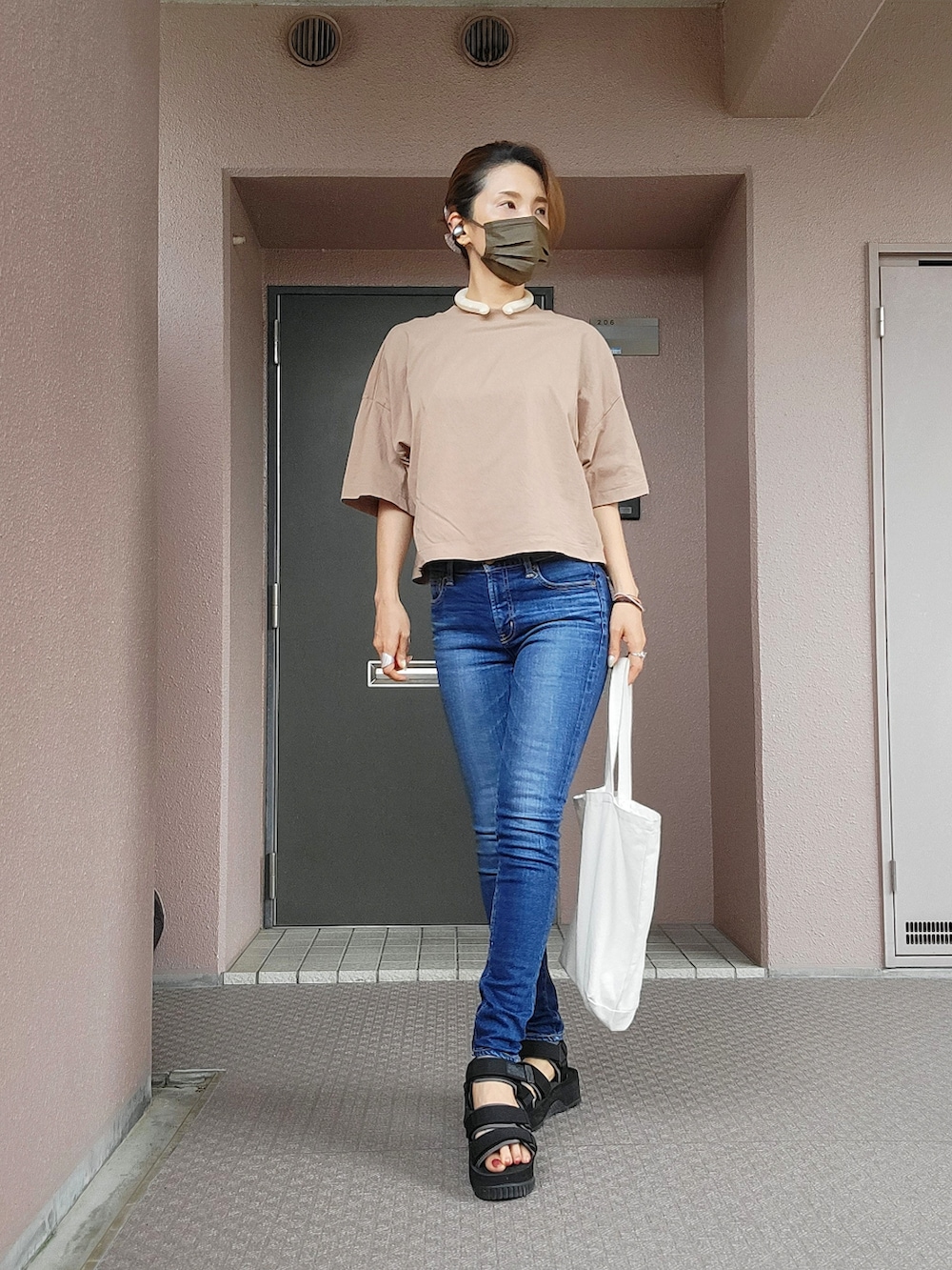 ブルー系のデニムパンツ、ブラック系のサンダル、ブラウン系のTシャツ/カットソーを着用したレディースの夏コーディネートの3枚目の写真