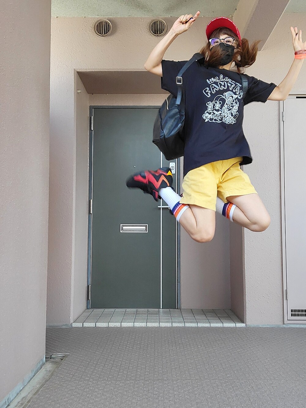 ブラック系のTシャツ/カットソー、イエロー系のパンツ、ブラック系のスニーカーを着用したレディースの秋コーディネートの2枚目の写真