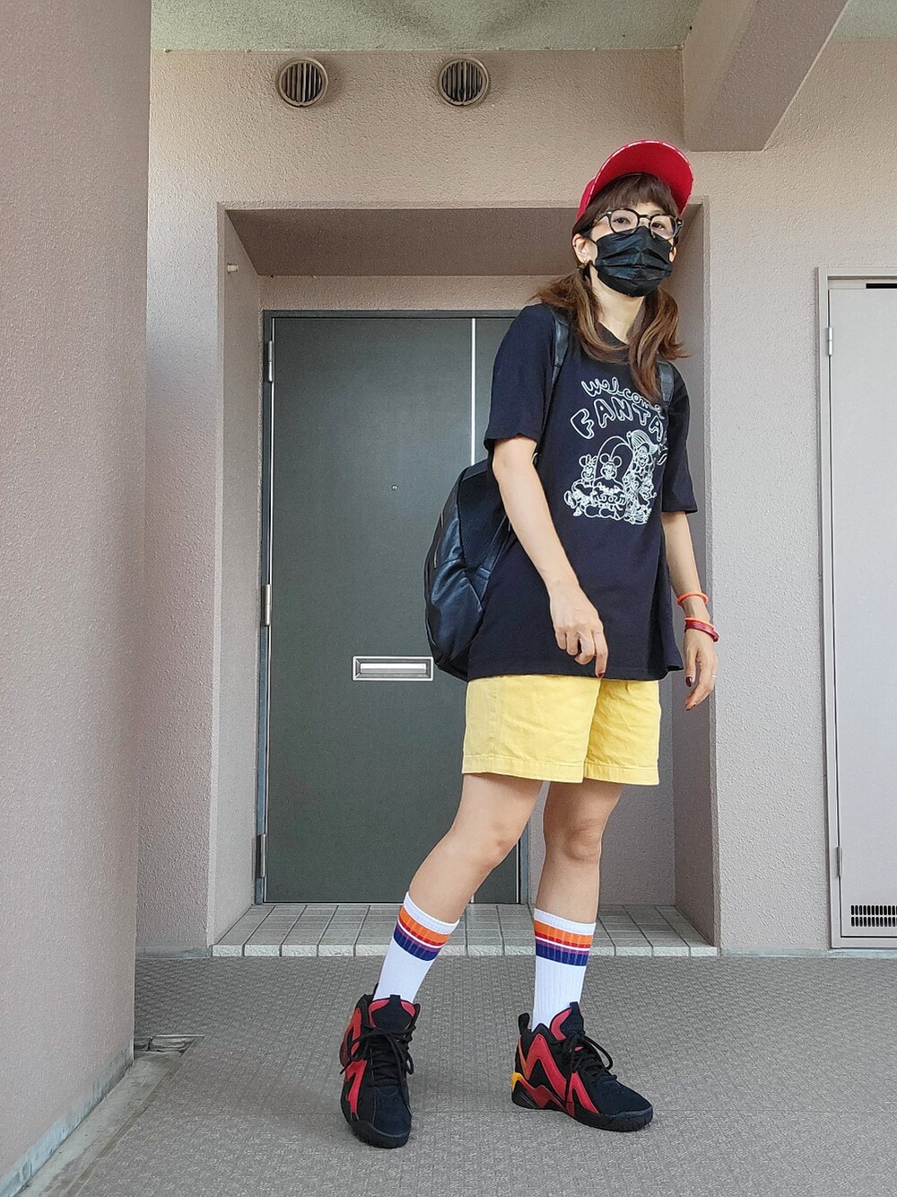 ブラック系のTシャツ/カットソー、イエロー系のパンツ、ブラック系のスニーカーを着用したレディースの秋コーディネートの3枚目の写真