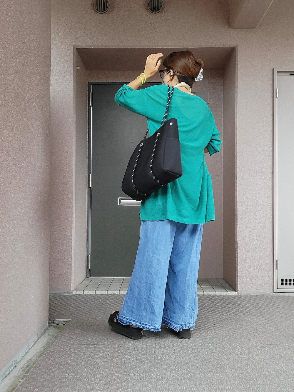 ブラック系のトートバッグ、ブルー系のデニムパンツ、ブラック系のサンダルを着用したレディースの秋コーディネートの2枚目の写真